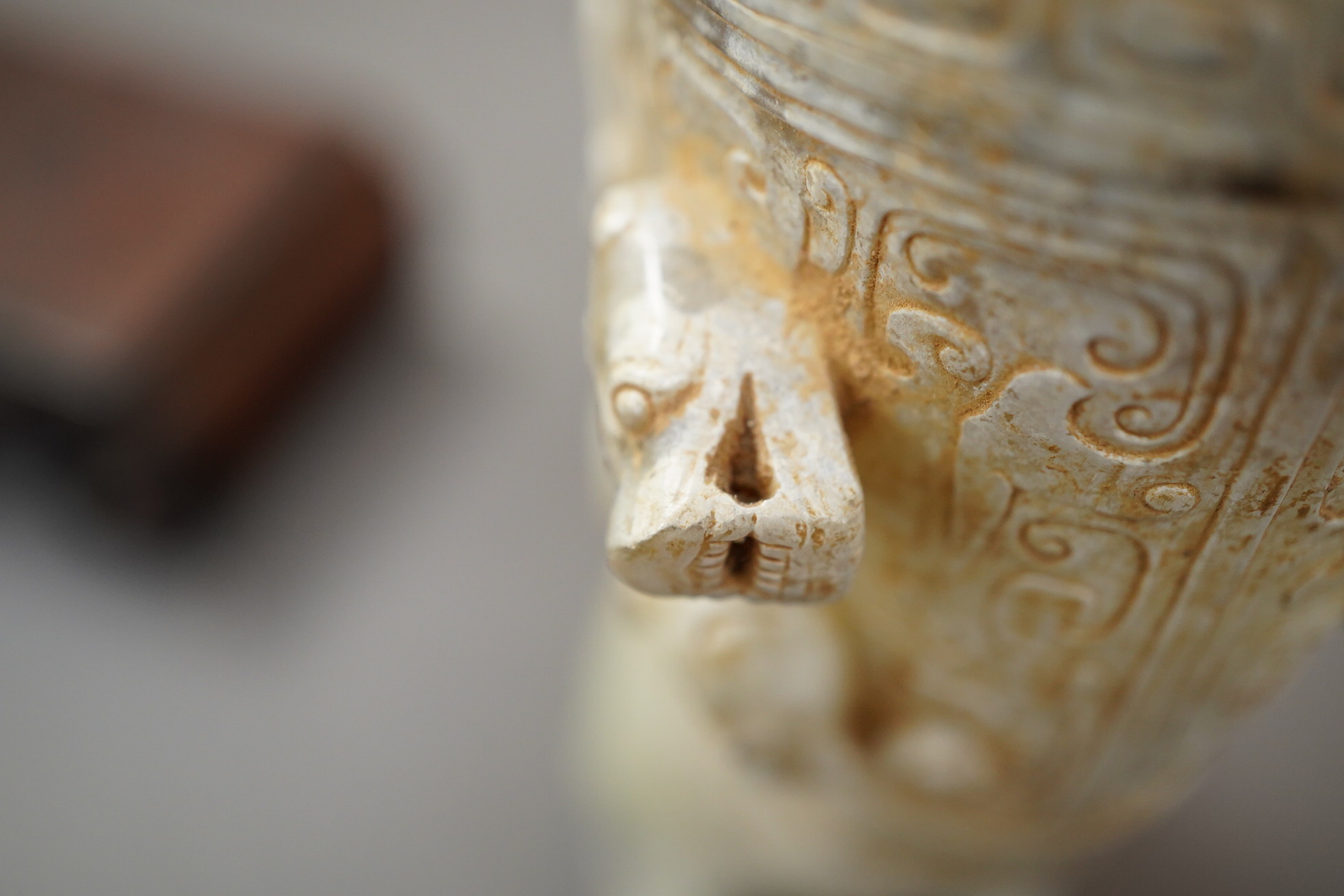 A large Chinese archaistic pale celadon and calcified jade rhyton